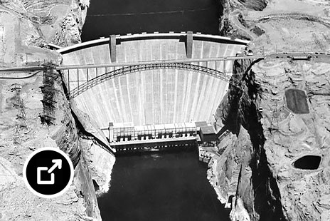 Black-and-white aerial view of a concrete dam set in a rock canyon